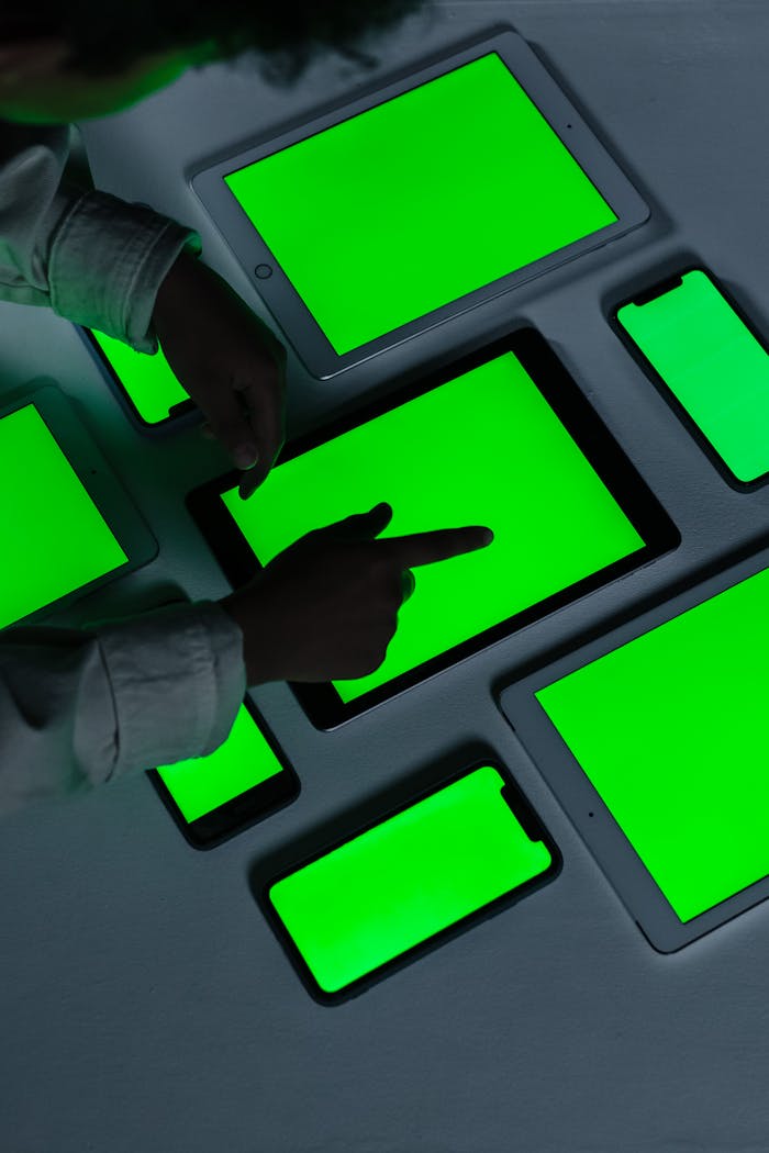 Person interacts with various green screen tablets and phones indoors.